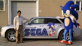 Yuji Naka junto a un auto tematico de SEGA